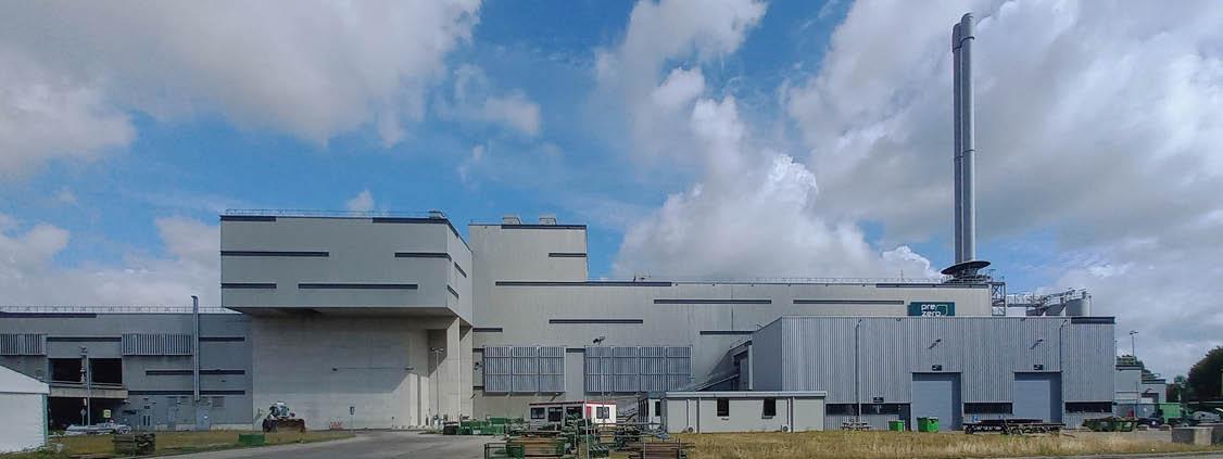 Exterior of a PreZero industrial facility with a tall exhaust stack under a cloudy sky.